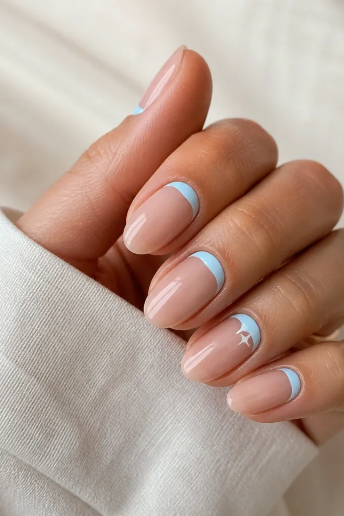 Short almond nails with a nude base; a sky-blue reverse French at the cuticle forms a curved half-moon, leaving the rest nude; one accent nail has a tiny white star near the cuticle; glossy.