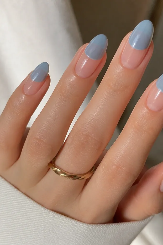 Almond nails with a sheer nude base. The top half of each nail is covered in a translucent sky-blue overlay, leaving the bottom half clear. The overlay has a smooth edge with a glossy finish.