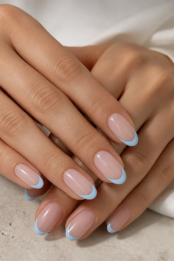 Medium oval nails with sheer nude base. The French tip has a sky blue outline around the perimeter, leaving a clear center area within the tip. Glossy topcoat, crisp outline.