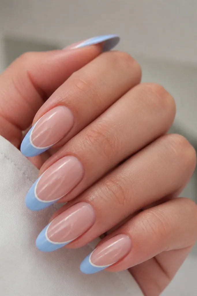 Long oval nails with sheer nude base. A micro thin white line sits between the nude and the sky blue French tip, creating a layered border. Sky blue tip is glossy and crisp, with no glitter.