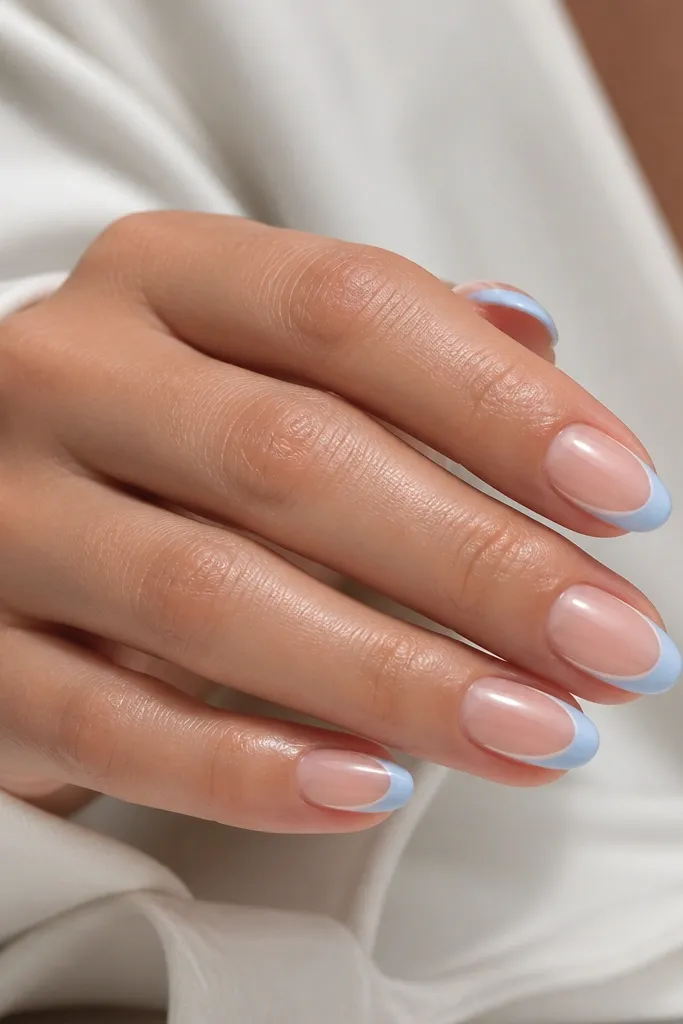 Short almond nails with sheer nude base. French tips are sky blue with a standard smile. On each nail, there's a single thin diagonal micro line in white starting near the side of the tip and heading toward the center.