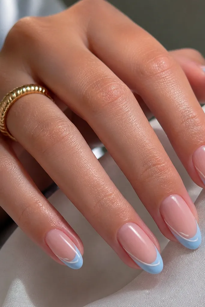 Medium oval nails with sheer nude base. Sky blue French tips are glossy and crisp. On one sidewall near the tip, there's a tiny white micro swirl line accent on each nail.