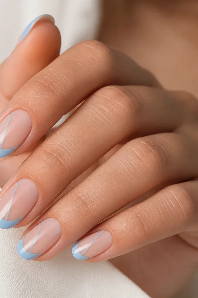 Nude base nails with sky-blue French tips. On each nail, a thin diagonal sky-blue line runs from the sidewall toward the center near the tip area, like a slash accent. Glossy finish.