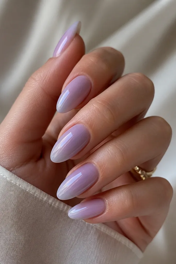 Almond nails in a soft lavender haze. A micro French fade sits at the tip in slightly lighter lavender, blended so it looks like a cloud. Glossy finish.