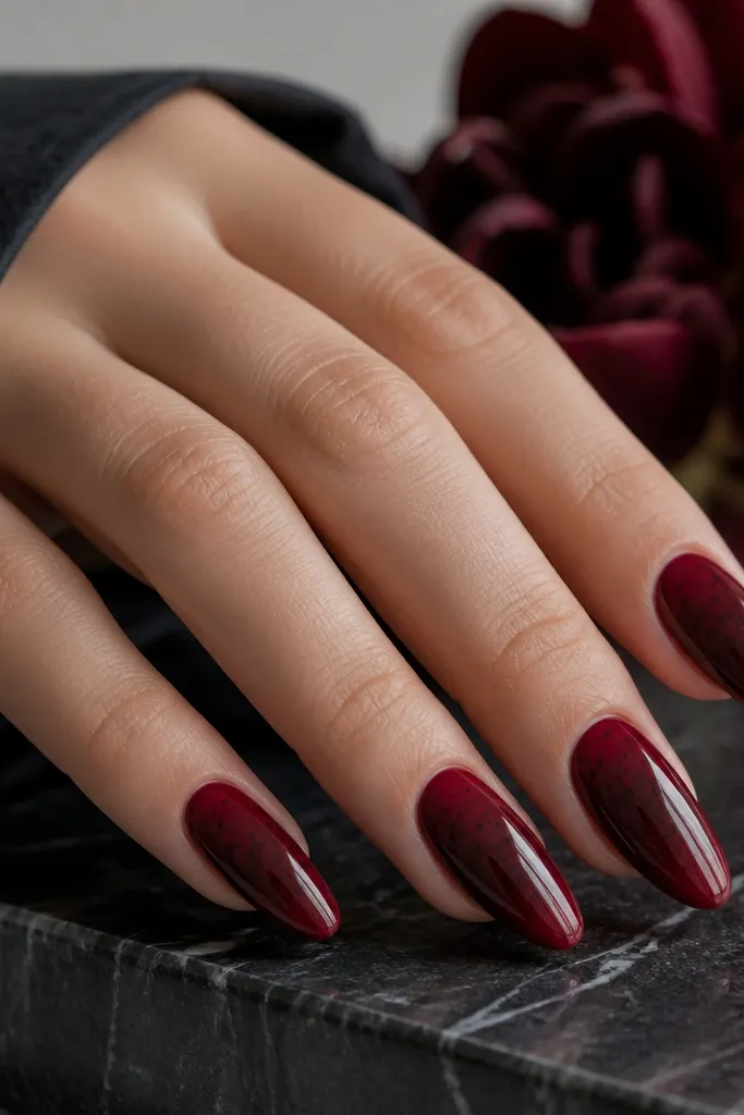 Almond nails with deep berry red base. Over part of the nail is a sheer black veil gradient that fades toward the tip, with glossy finish.