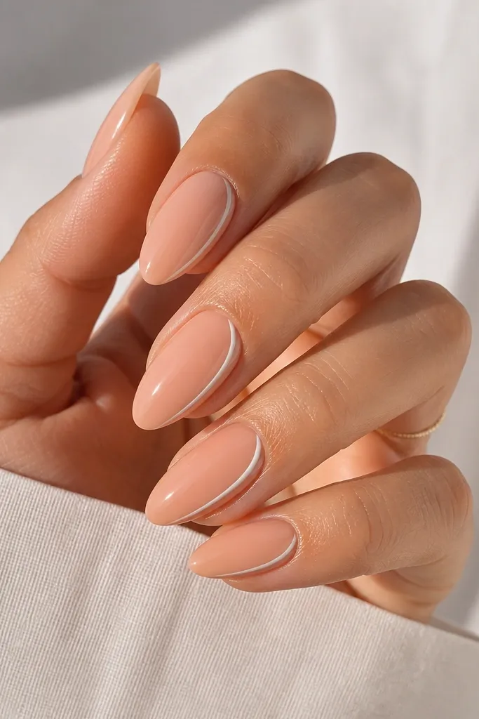 Glossy peach nude almond nails with a super thin white line running along one sidewall from mid-nail to tip; the center stays peach.