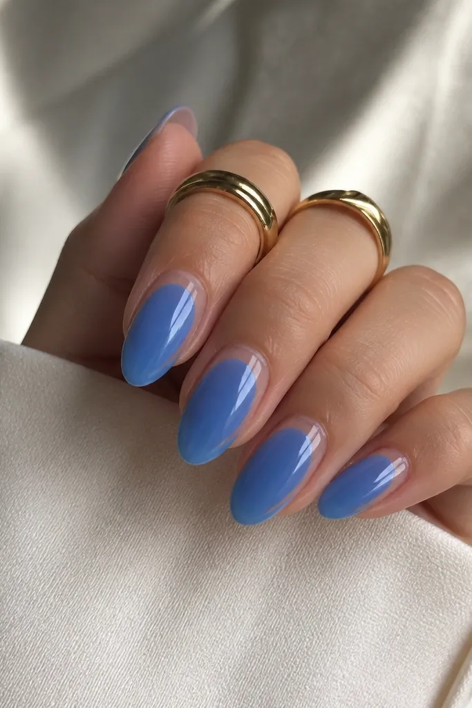 Glossy jelly blue almond nails with a thin clear outline that frames the cuticle area like a mini rectangle; the center stays solid blue.