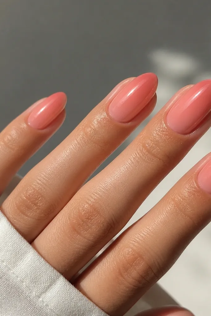 Milky pink almond nails with a glossy coral jelly overlay that looks translucent, especially at the tip, with no extra nail art.
