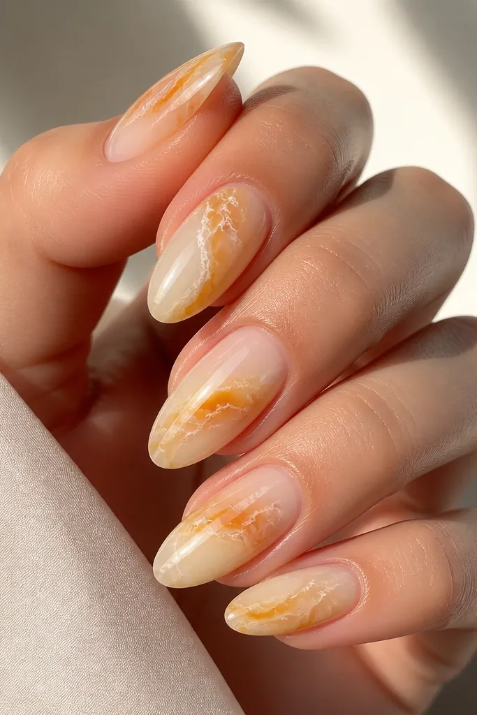 Almond nails with semi-translucent yellow and orange marbling over a milky base; fine white veins and a glossy shine.