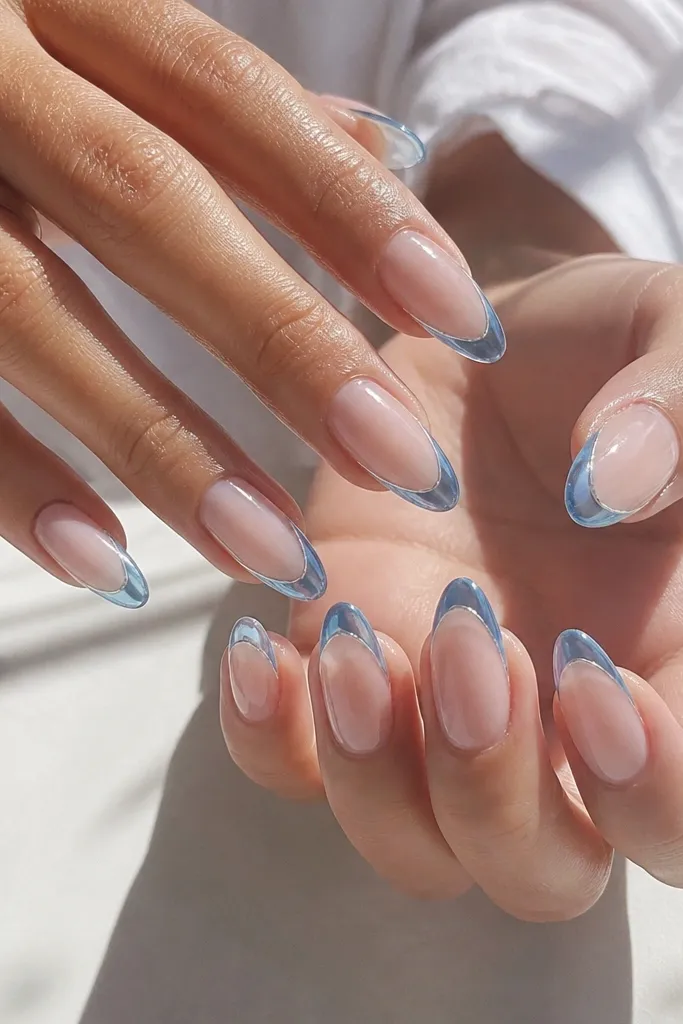 Clear nude almond nails with glossy translucent blue tips, like stained glass; thin white outline around the tip area.