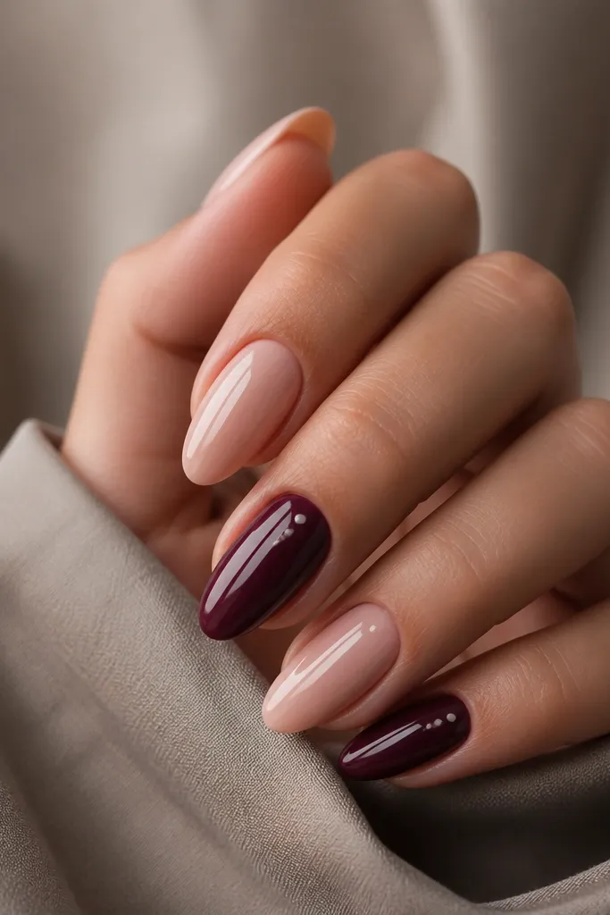 Almond nails with deep berry base on accent nails and sheer nude on others; accent nails have tiny white highlight dots like blueberry shine; glossy.