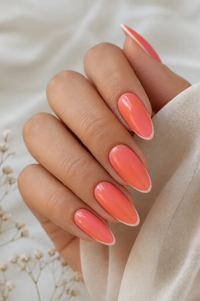 Almond nails with coral ombre fading from cuticle to tip and a thin white line at the very edge; glossy.