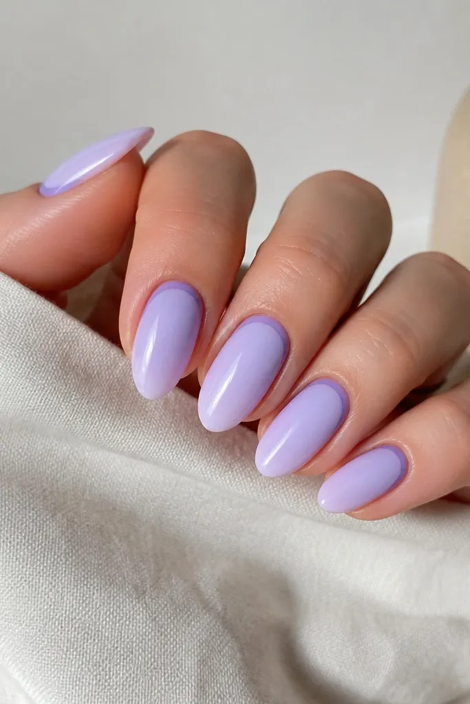 Almond nails in a lavender milky base. Around the cuticle, there is a thin halo line in a slightly deeper purple. The rest of the nail stays clean and glossy.