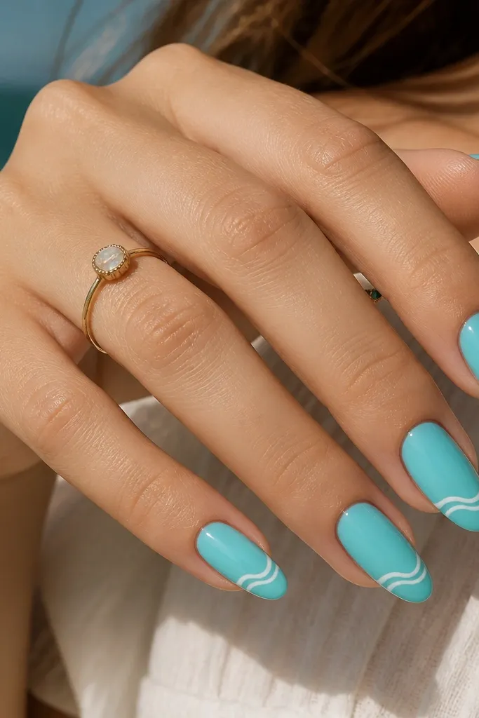 Almond nails painted turquoise. A thin white wave line runs horizontally near the tip on each nail, like a small surf crest. Glossy top coat makes the turquoise look deep and watery.