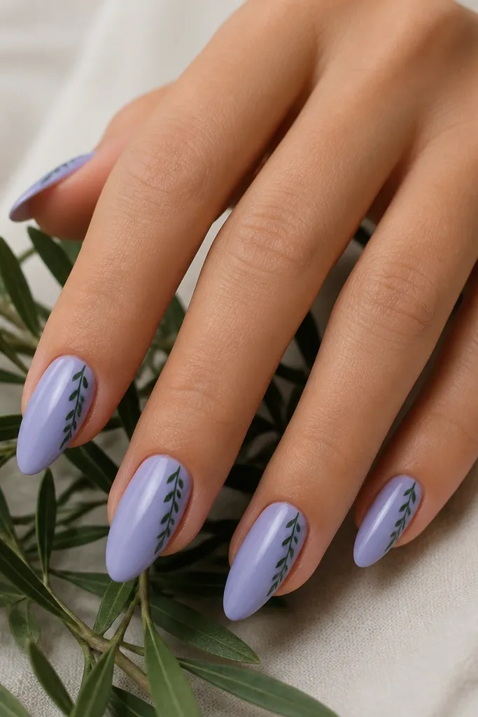 Almond nails painted lavender milk (soft periwinkle). On each nail there is a thin diagonal stripe starting near the cuticle on one side, with tiny leaf marks along the stripe, all in dark forest green.