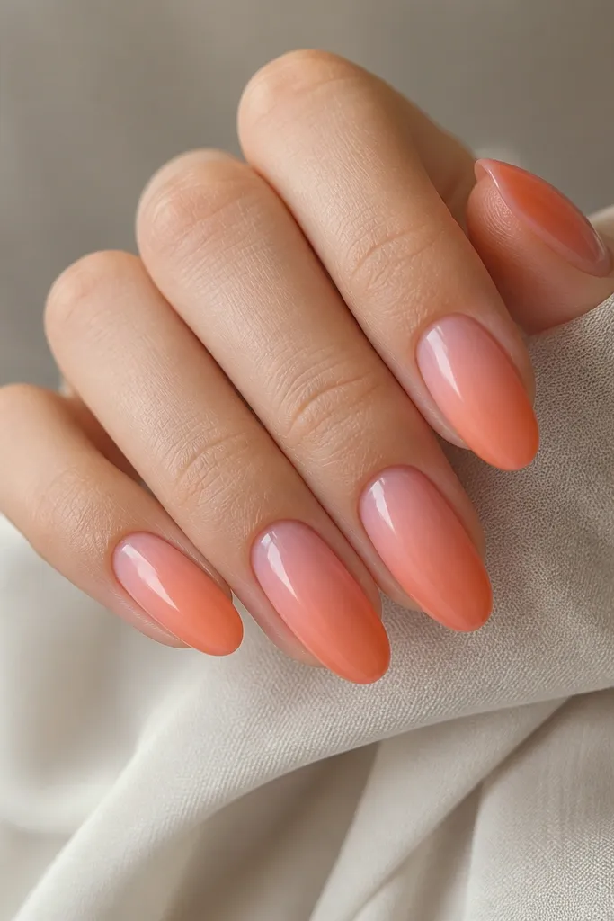 Medium oval nails with a sheer rose-pink base and a smooth gradient orange that starts halfway down the tip and fades into pink. The blend is soft with no hard line.