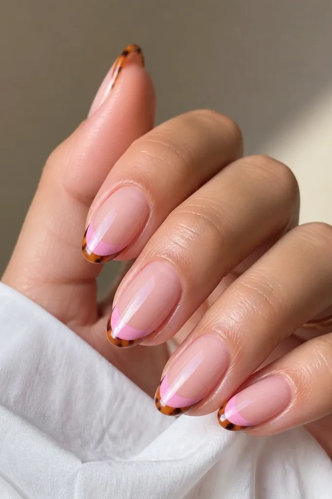 Nails with a pink French base at the tip and a thin orange tortoiseshell border along the very edge. The pattern looks like tiny irregular spots and lines, glossy and defined.