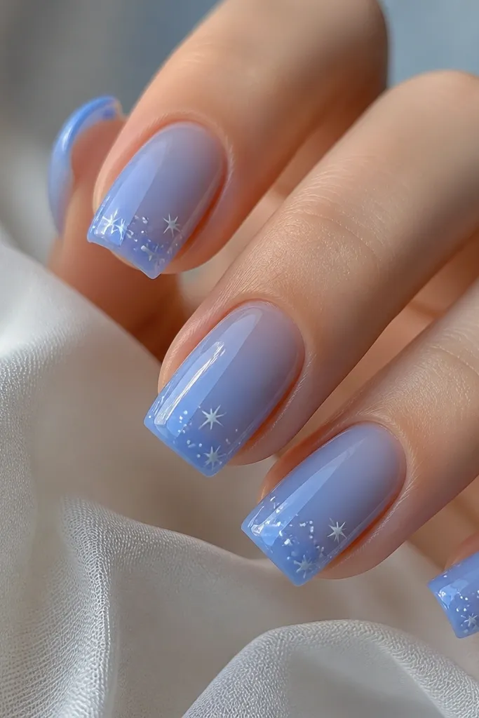Glossy sheer blue base with tiny white stars and dots clustered near the tip corners; square nails with sharp edges.