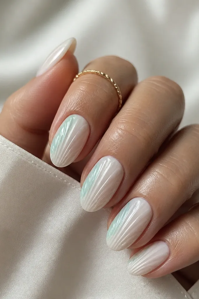 Short almond nails in milky white. Shell ridges are centered. On one side of each nail, there's a soft watercolor seafoam fade that looks like it was brushed on and feathered. The other side stays plain milky white.