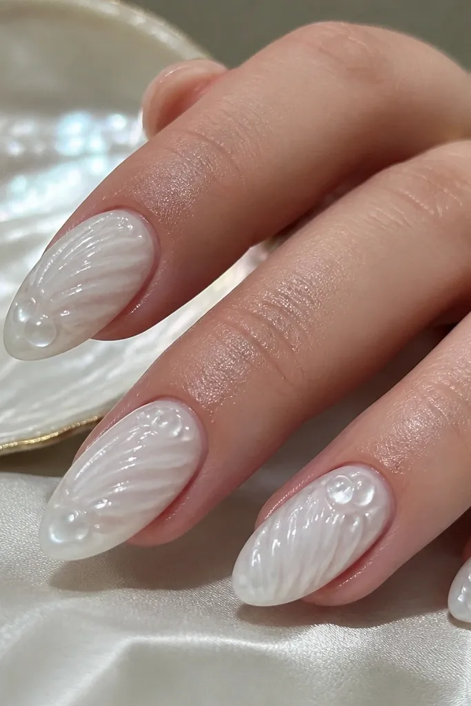 Glossy milky-white nails with a clear jelly top layer that looks like shallow water. Tiny raised bubble dots sit under the clear coat near the free edge, with one or two slightly larger bubbles catching light. The shell pattern is subtle and smooth, with a soft curved ridge on each nail and a clean, salon-shaped almond silhouette.